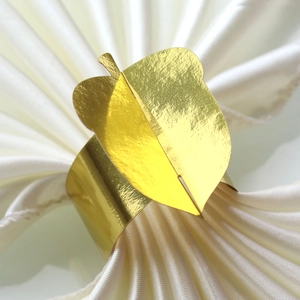 Elegant gold leaf napkin ring with metallic finish on white satin napkin for holiday party