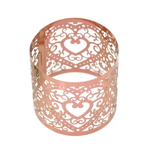 Detail of rose gold laser-cut napkin ring featuring an intricate hollow heart pattern
