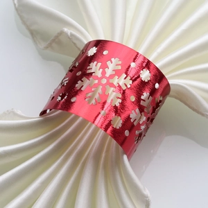 Close-up of red metal snowflake napkin ring with intricate hollow design on satin cloth