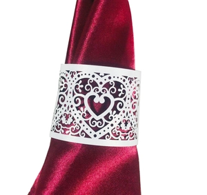 Detail of laser-cut white heart napkin ring on a deep red silk fabric holder