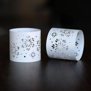 Detailed view of white pearlescent paper napkin rings with delicate laser cut snowflake pattern