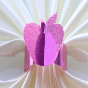 Macro shot of mirror-finish pink butterfly napkin ring on elegant white silk napkin