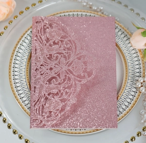 Detail of pink glitter laser-cut invitation card with delicate lace pattern on a plate
