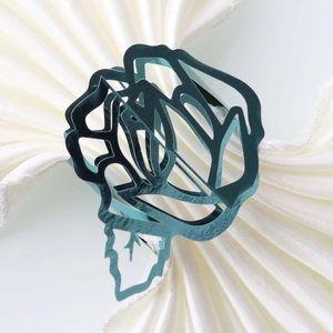 Detailed view of dark teal hollow rose napkin ring on a beige silk table cloth