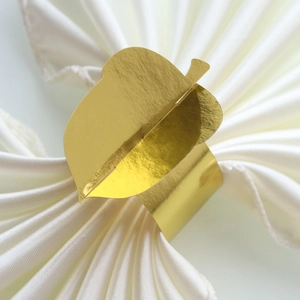 Close-up of a golden leaf napkin ring on a white silk napkin for table decoration