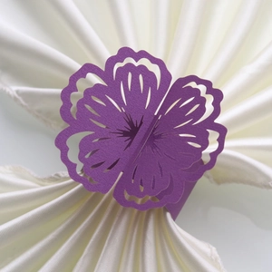 Detail of laser cut purple paper napkin ring with floral hollow pattern for wedding decor