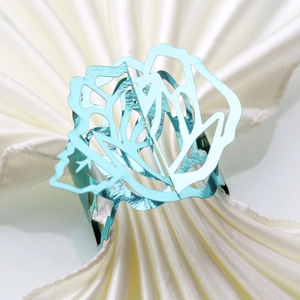 Macro detail of a hollow rose napkin ring in light blue metal finish on white satin