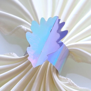 Détail du rond de serviette holographique en forme de feuille sur soie blanche