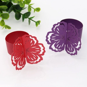 Detail of laser-cut paper napkin rings in red and purple floral designs for weddings