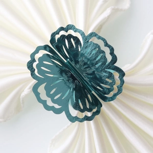 Macro shot of teal hollow floral napkin ring on a white folded cloth