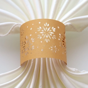 Detailed laser-cut silver snowflake napkin ring made of pearlescent paper on white fabric