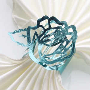 Close-up of teal metallic rose napkin ring with intricate laser-cut hollow floral details