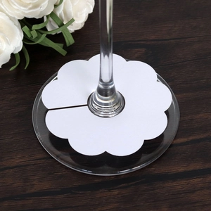 Detail of flower-shaped white paper wine glass card placed on a glass stem for weddings