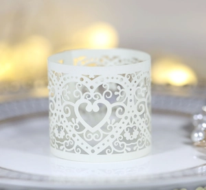 Macro shot of laser-cut heart pattern on cream white paper napkin ring for weddings