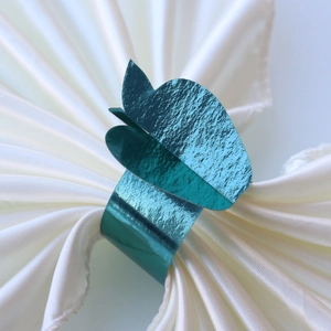 Detail of teal butterfly napkin ring with metallic texture on white satin fabric