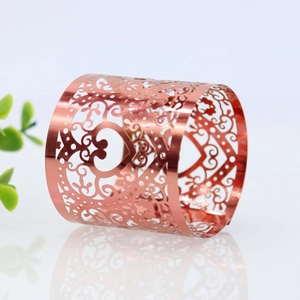 Macro shot of rose gold heart napkin ring with intricate hollow laser-cut floral patterns