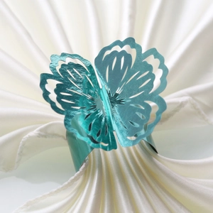 Macro detail of a turquoise metallic butterfly napkin ring with hollow floral patterns