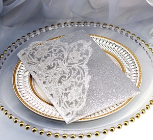 Intricate laser-cut vine patterns on silver glitter wedding invitation with metallic finish