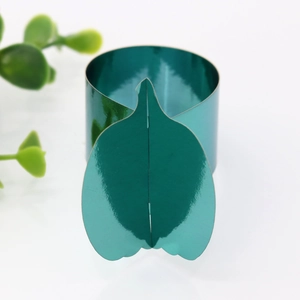 Close-up of a teal metallic napkin ring with leaf ornament and mirror finish