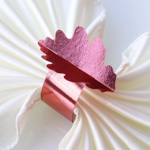 Détail macro d'un rond de serviette feuille or rose sur une serviette en soie blanche