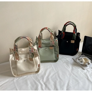 Detailed shot of multi-pocket canvas tote bags in white, green and black with floral handles