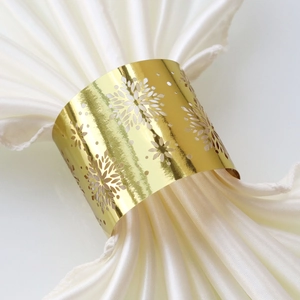 Macro view of golden cutout snowflake metal napkin ring on a white silk fabric