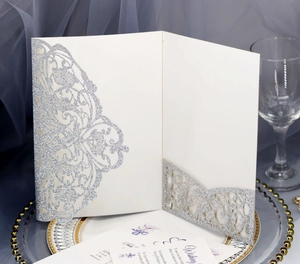 Detail of silver glitter laser cut wedding invitation with intricate lace hollow patterns
