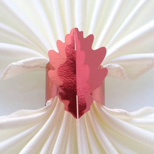Détail macro du rond de serviette feuille d'érable rouge métal sur soie blanche