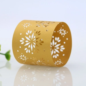 Detail view of golden laser-cut snowflake paper napkin rings for elegant Christmas tables