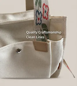 Detail of canvas tote bag with floral embroidery strap and metallic rivet hardware