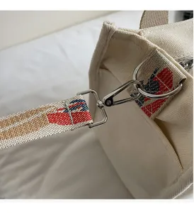 Detail of silver metal swivel hook and textured jacquard shoulder strap on canvas tote