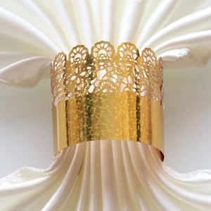 Close-up of golden crown lace napkin ring with glitter detail on white satin cloth