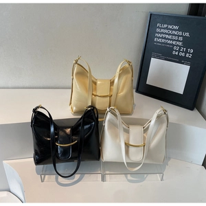 Close-up of minimalist hobo bags in black and cream with gold buckle detail