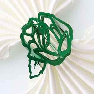 Detail of dark green laser-cut rose napkin ring on a white folded cloth for wedding decor