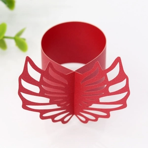 Detail showing red laser-cut paper napkin ring with intricate hollow wing design
