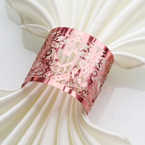 Detail of rose gold heart napkin ring with laser-cut floral pattern on white linen