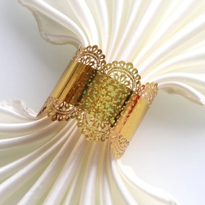 Detail of laser-cut gold lace napkin ring with sparkling glitter on white cloth