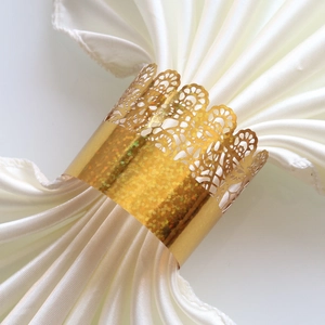 Close-up of golden laser-cut lace napkin ring with elegant crown pattern on white satin