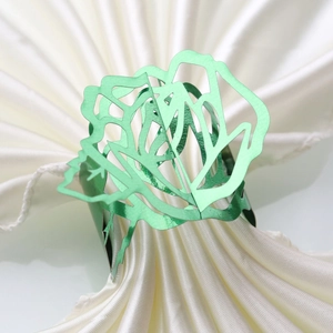 Detailed macro view of green hollow rose napkin ring on a white satin fabric background