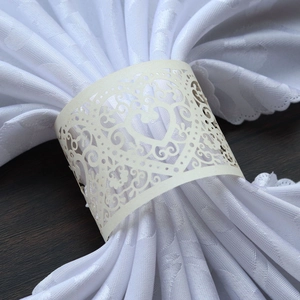 Detail of laser-cut heart pattern on cream paper napkin ring with floral hollow design