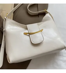 Close-up of off-white dumpling bag with golden metal buckle and textured leather detail