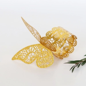 Detail of laser-cut butterfly napkin ring with golden glitter finish on white surface