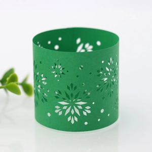 Detail of green laser-cut paper napkin ring with intricate snowflake pattern for Christmas