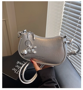 Close-up of a silver crescent bag with textured metallic leather and a knotted shoulder strap