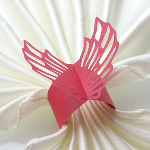 Detail of red laser-cut butterfly napkin ring on white silk fabric for wedding decor
