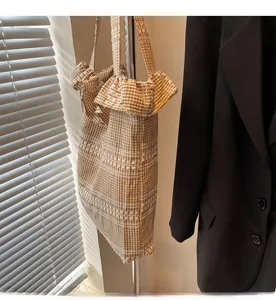 Détail du sac cabas en toile à carreaux avec bords à volants et broderie blanche