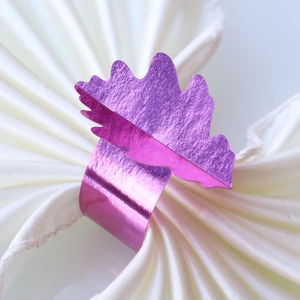 Détail d'un rond de serviette feuille métallique violette sur du satin plissé blanc