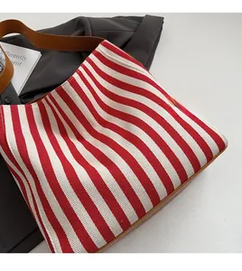 Top view of red and white striped canvas tote bag with brown leather handles and base