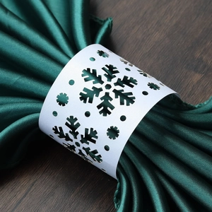 Laser-cut white snowflake napkin rings on green fabric for Christmas table decor