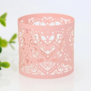Close-up of laser-cut paper napkin ring with heart patterns and vine lace details